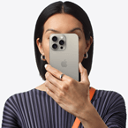 Osoba si před obličejem drží iPhone 15 Pro Max, aby skryla svou identitu